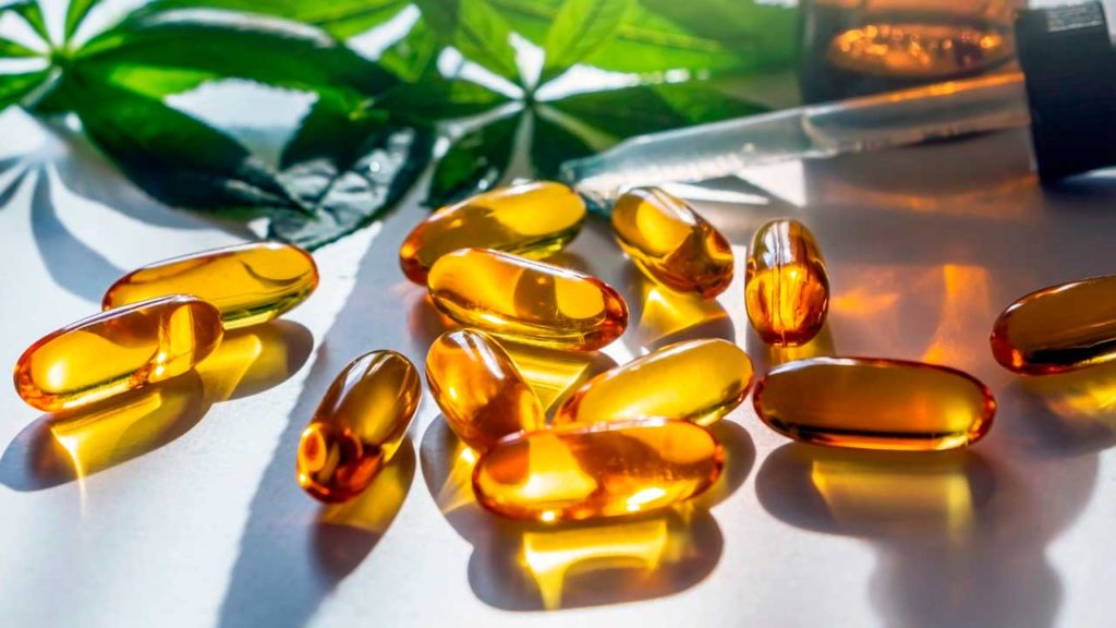 Several golden yellow colored CBD sublingual capsules showing one of the best ways to ingest CBD