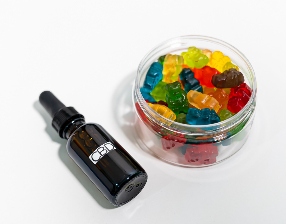 tincture vs. edible comparison on a picture: a dropper bottle and a jar with gummies