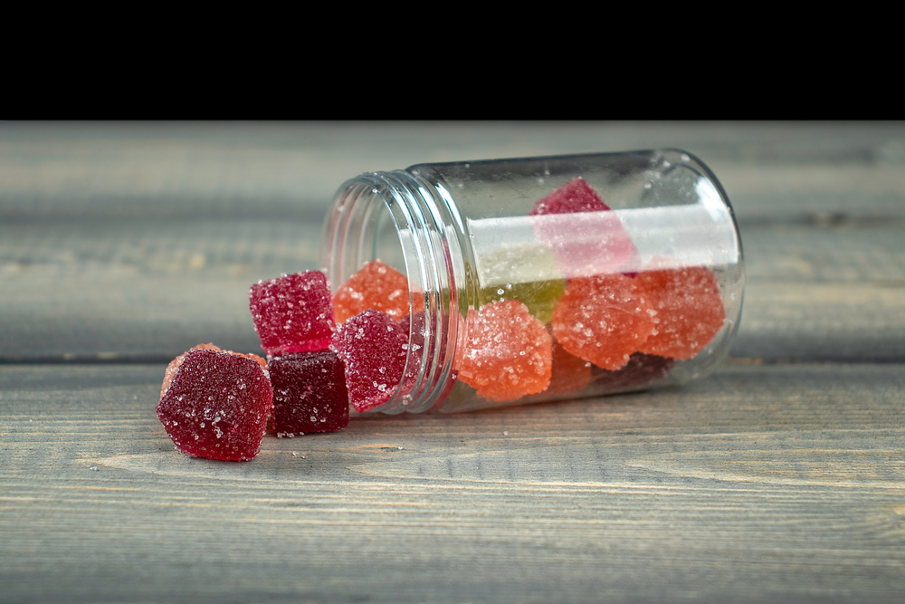 A glass jar missing its lid with premium quality, sugar-coated strawberry HHC cannabinoid gummies