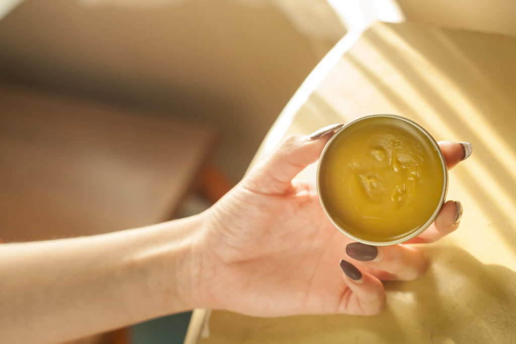 The woman holds a CBD muscle rub, ready to apply it after an intense workout to soothe muscles.