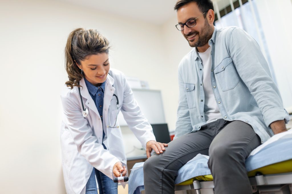 The neurologist tests the knee reflex and carefully observes the patient's leg.